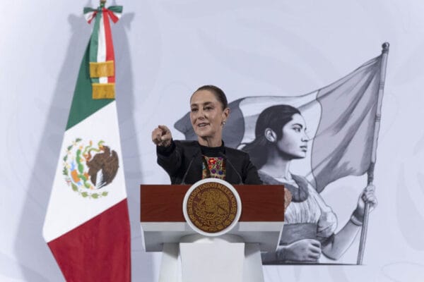 Presidenta Claudia Sheinbaum habla en conferencia de prensa en Palacio Nacional, con pantallas de gráficas de inversión social a su espalda.