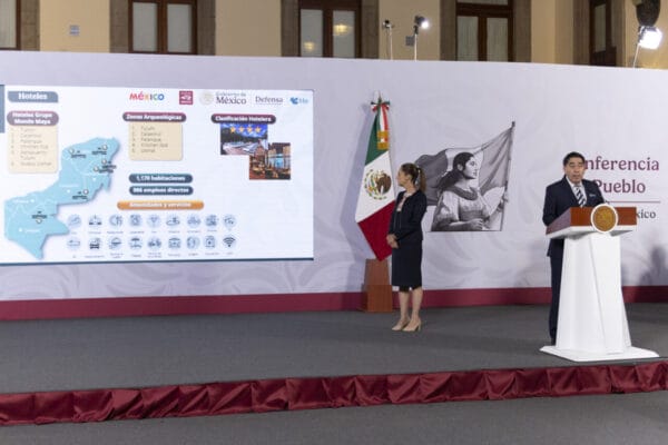Presidenta Claudia Sheinbaum escucha al director del Tren Maya durante la conferencia en Palacio Nacional, gráfica de pasajeros en pantalla.