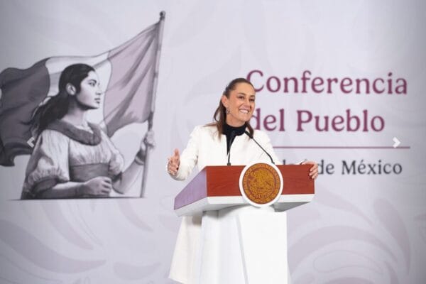 Presidenta Claudia Sheinbaum habla frente al escudo nacional en conferencia de prensa matutina en Palacio Nacional.
